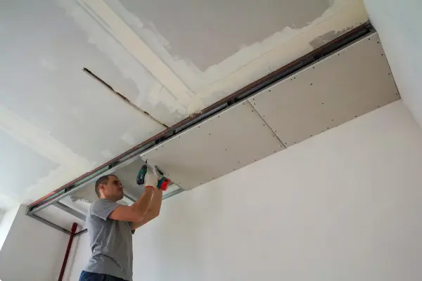 contractor finishing drywall ceiling with joint compound