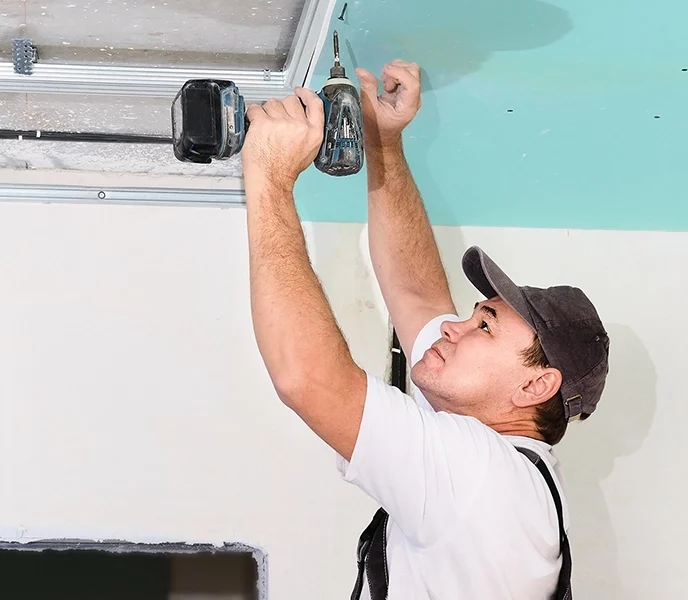 Drywall installer mounting ceiling panels - professional drywall services Markham by Express Drywall Services.