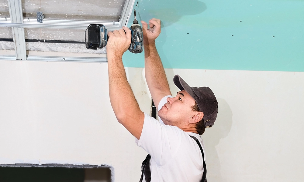 Drywall installer mounting ceiling panels - professional drywall services Markham by Express Drywall Services.