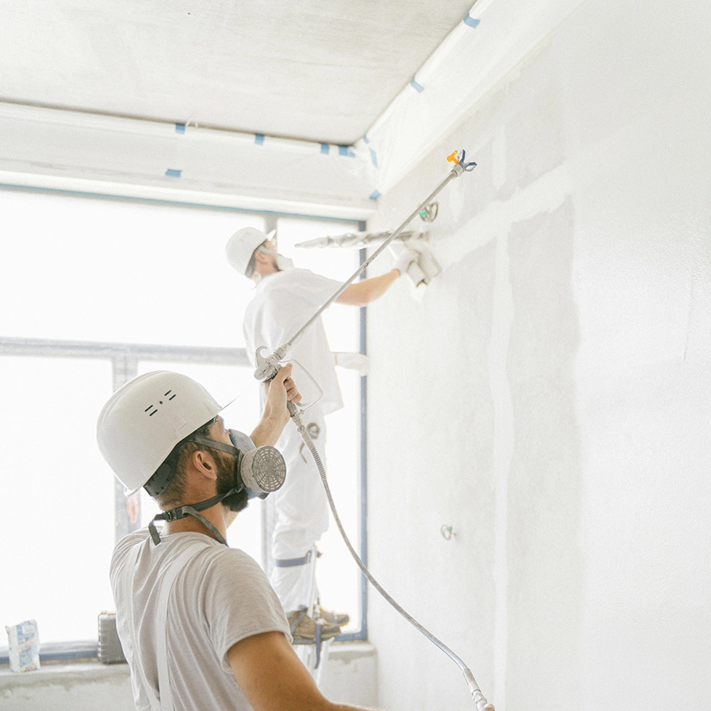 Express Drywall Services crew applies joint compound using spray tools during drywall taping and mudding on finished walls.