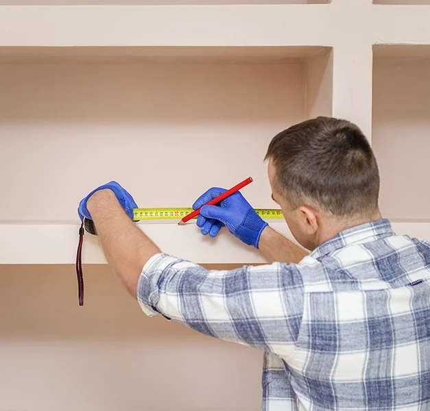 Contractor measuring drywall shelving - expert drywall services Brampton by Express Drywall Services.