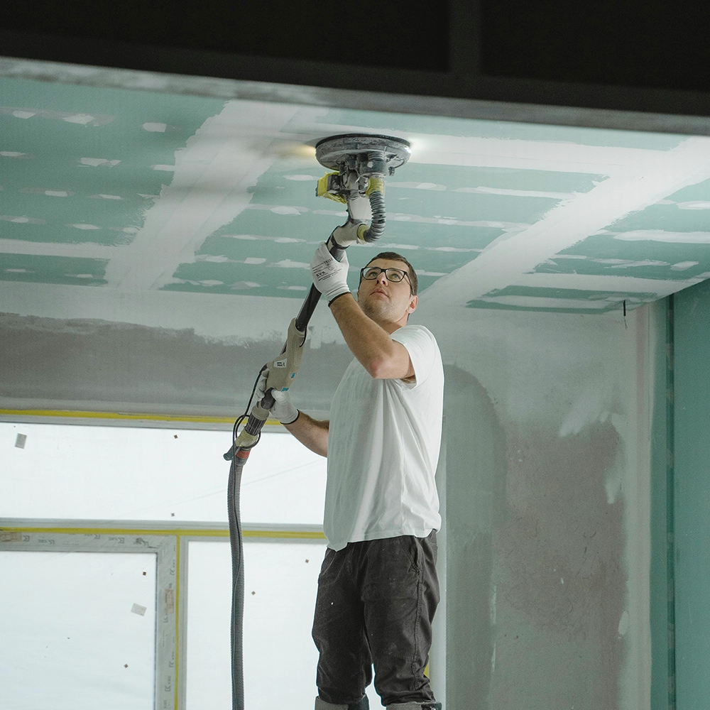 Contractor sanding ceiling joints during drywall repair by Express Drywall Services