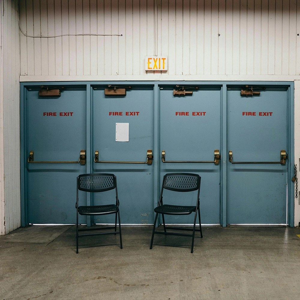 Row of fire-rated commercial metal door installations in an event or warehouse space by Express Drywall Services.