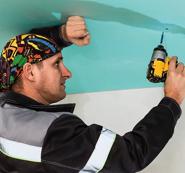 Drywall installer securing ceiling panels - expert drywall services Hamilton by Express Drywall Services.