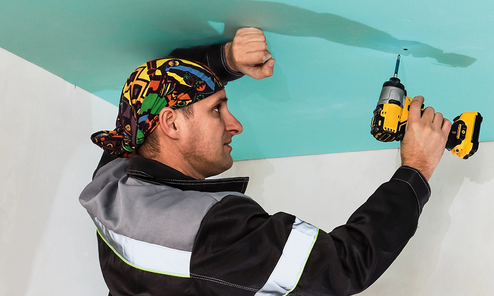 Drywall installer securing ceiling panels - expert drywall services Hamilton by Express Drywall Services.