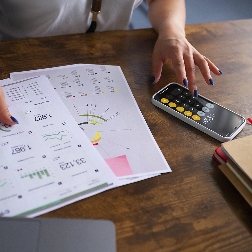 Person reviewing utility bills and calculator showing high costs, related to insulation installation by Express Drywall Services residential services.