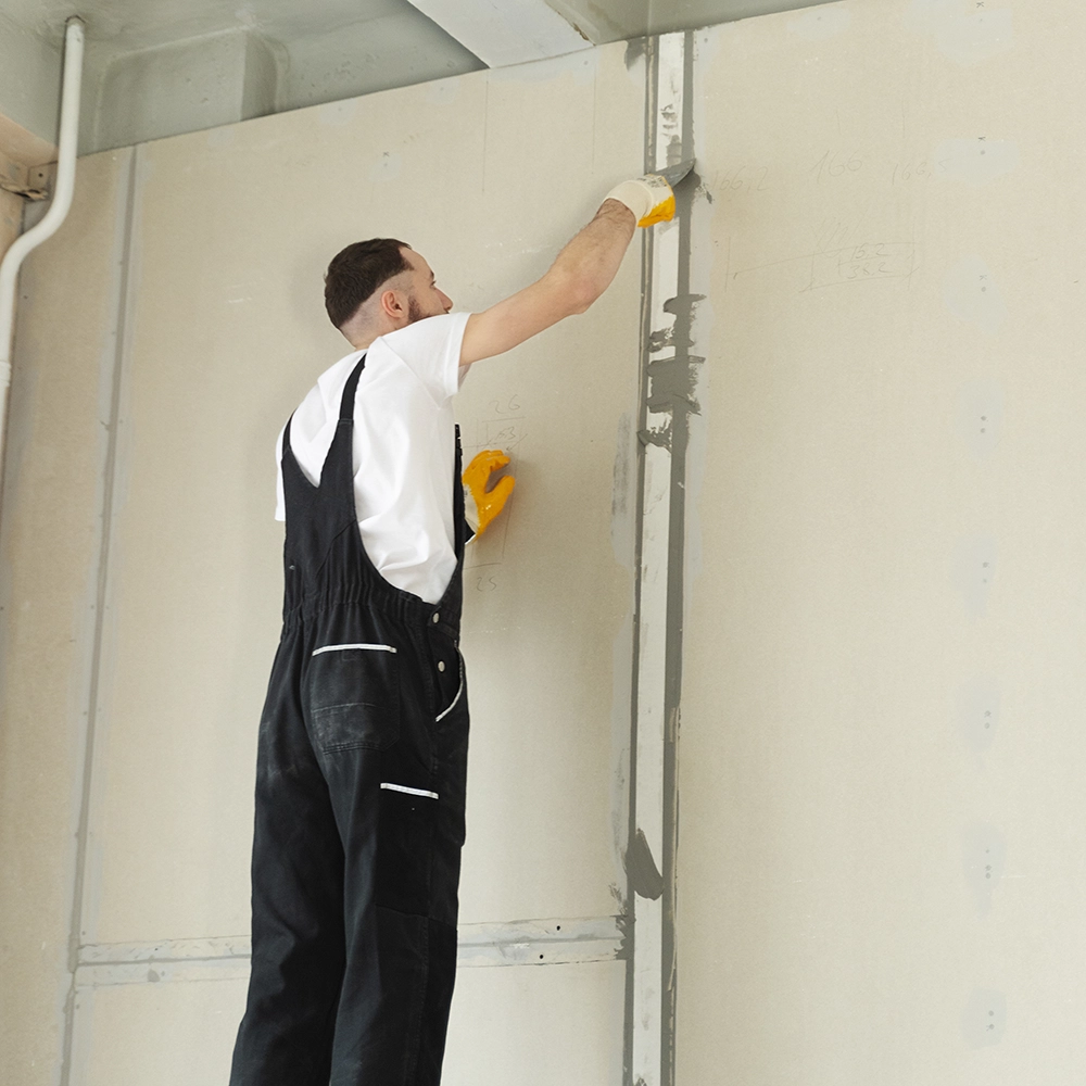 Worker from Express Drywall Services applies joint compound for residential taping and mudding on vertical seams.