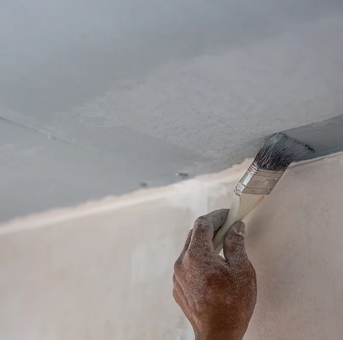 Worker applying paint to finished drywall ceiling — expert drywall services Oshawa by Express Drywall Services.