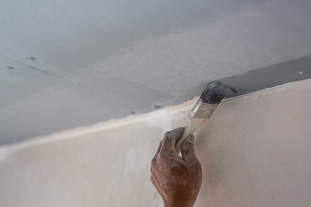 Worker applying paint to finished drywall ceiling — expert drywall services Oshawa by Express Drywall Services.