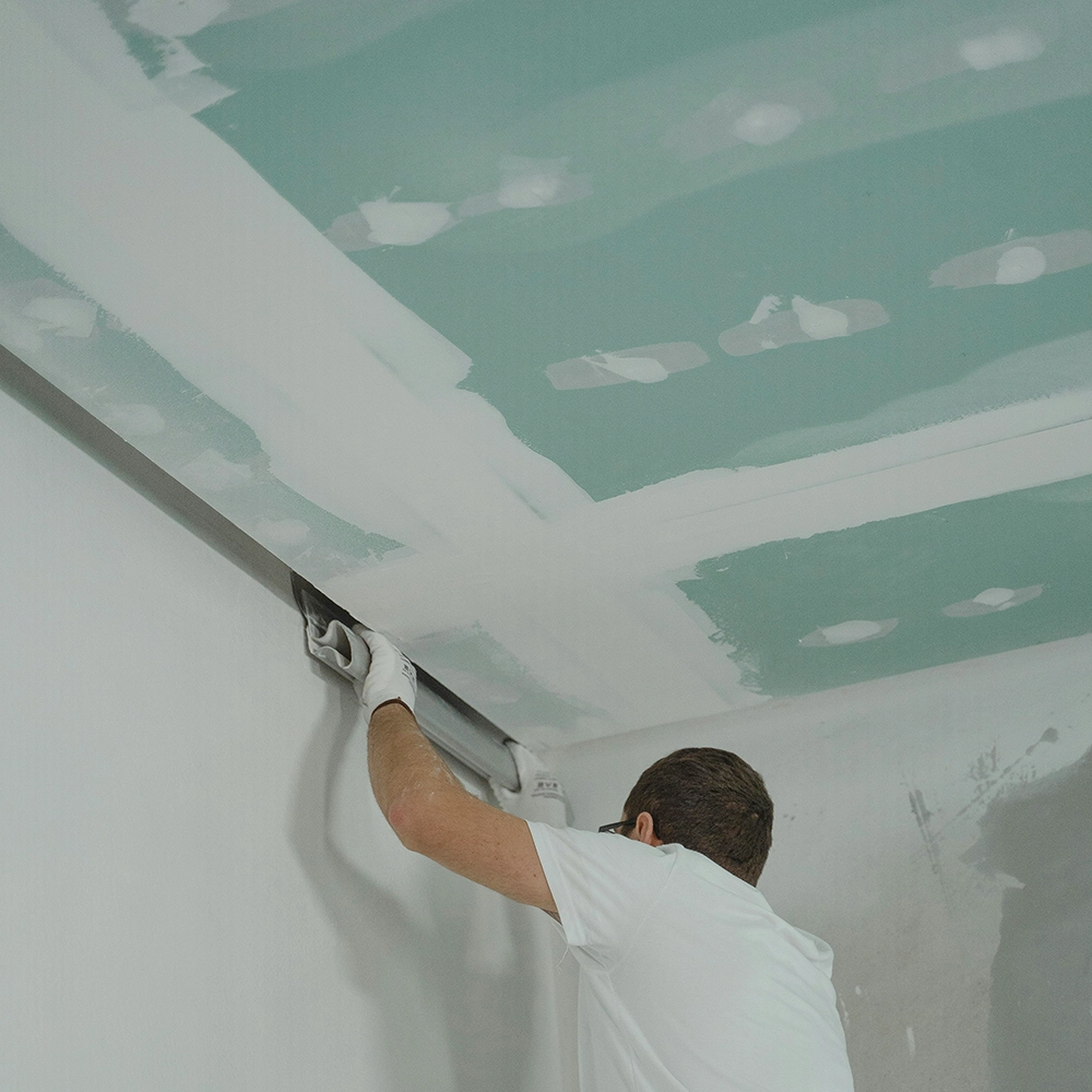 Express Drywall Services technician performing precise drywall taping and mudding on a ceiling joint for a seamless finish.