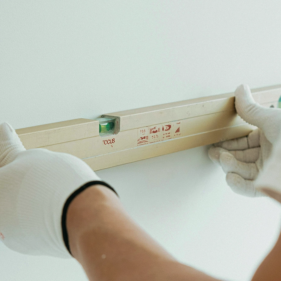 Worker checking wall alignment with level tool for accurate framing setup