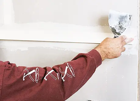 Technician applying mud over tape during residential taping and mudding by Express Drywall Services.