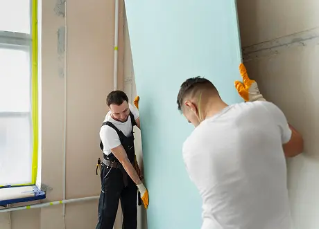 Two installers positioning a panel during commercial drywall installation by Express Drywall Services.