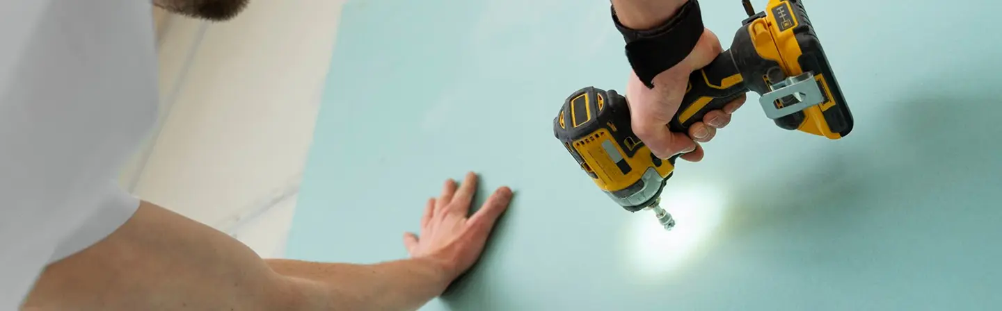 Worker fastening sheet during commercial drywall installation by Express Drywall Services.