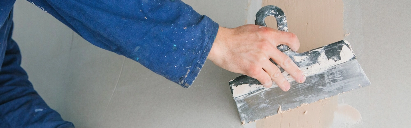 Technician applying mud to drywall seam during taping and mudding by Express Drywall Services.