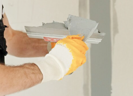 Worker preparing joint knife during drywall taping and mudding by Express Drywall Services.