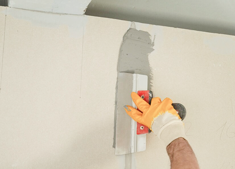 Worker applying joint compound during drywall repair by Express Drywall Services.