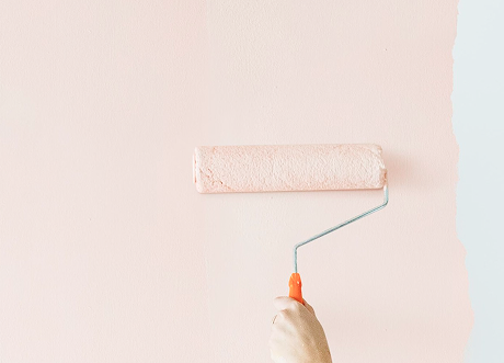 Roller applying fresh coat during commercial priming and painting by Express Drywall Services.