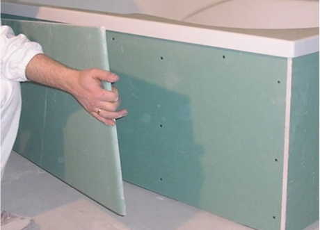 Installer applying panel during commercial moisture-resistant drywall installation by Express Drywall Services.