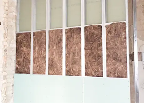 Framed wall with insulation for fire and sound separation in commercial space