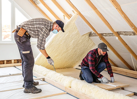 Two technicians installing batt insulation for attic soundproofing by Express Drywall Services.