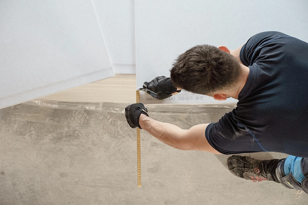 Worker uses measuring tape to prep panels for fire-resistant drywall installation in Toronto with Drywall Express Services.