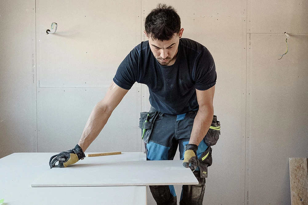 A drywall contractor precisely measures a sheet for fire-resistant drywall installation in Toronto with Drywall Express Services.