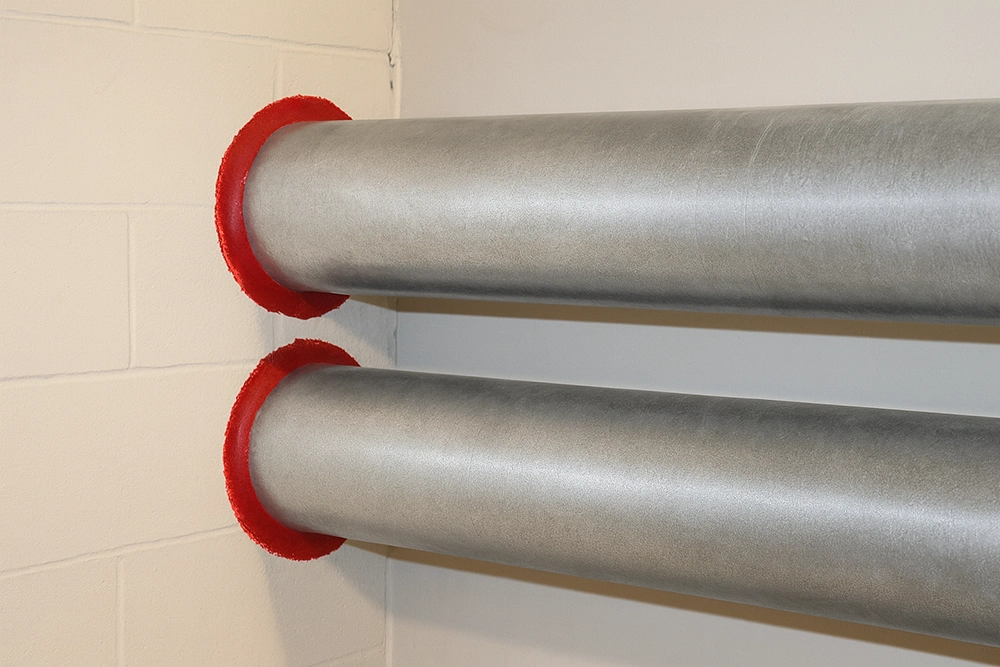 Close-up of completed fire caulking around large metal pipes — Commercial Fire Caulking in Toronto by Express Drywall Services