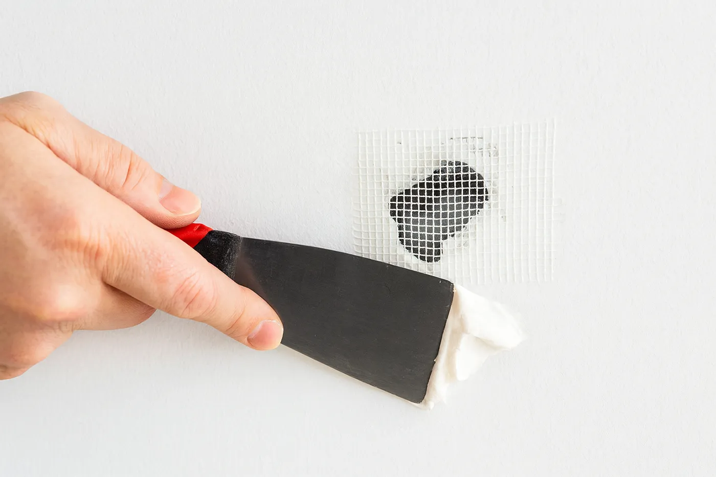 Applying patch compound over small hole during commercial drywall repair in Richmond Hill.