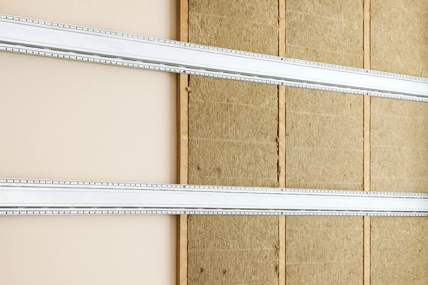 Commercial resilient channel installation in Richmond Hill – partially finished wall with acoustic insulation and mounted resilient bars.