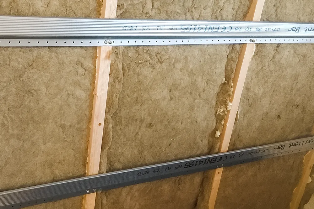 Commercial resilient channel installation in Richmond Hill – close-up of resilient channels mounted on wood studs with soundproof insulation.