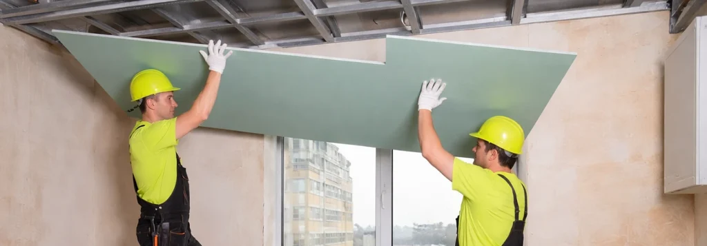 Drywall Contractors Near Me lifting drywall sheets into place by Express Drywall Services