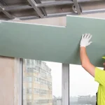 Drywall Contractors Near Me lifting drywall sheets into place by Express Drywall Services