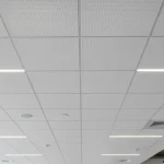 Installing drop ceiling tiles in modern open office by Express Drywall Services