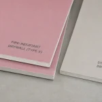 Two drywall panels side by side — pink fire-resistant drywall Type X and standard grey drywall, showing the difference between the two materials